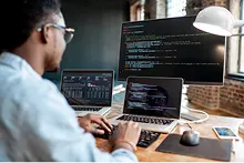 Développeur codant sur un PC devant 3 écrans